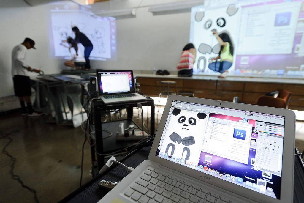 Small becomes large as teams of PEOPLE students cover the walls of a classroom with tape murals, including working from a computer-projected drawing of a panda. The group's project is part of an art internship taught by UW graduate student Jack Ohearn.