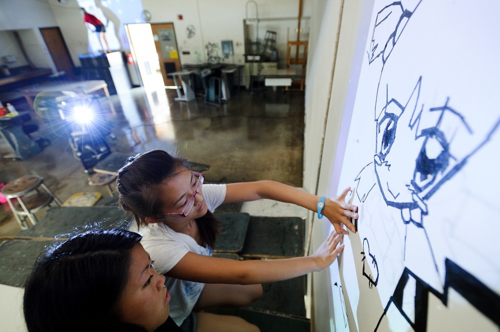 High school students Yer Lee, wearing glasses, and Mia Yang create a tape mural on a classroom wall at the Mosse Humanities Building as part of a six-week outreach program sponsored the Pre-College Enrichment Opportunity Program for Learning Excellence (PEOPLE).