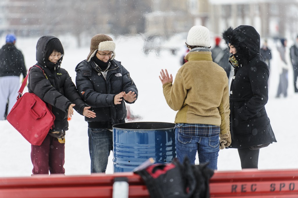 Spectators take a break to warm their hands at a fire as the snow comes down.