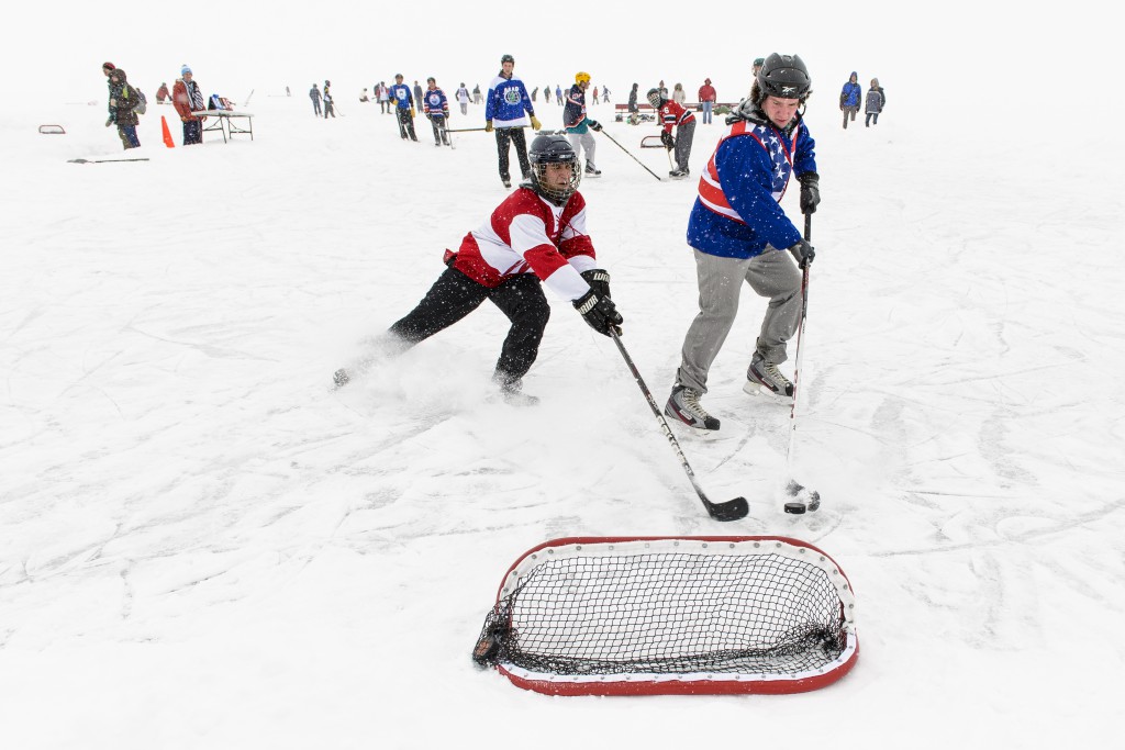 Teams of UW students stay warm and get into the Olympic spirit by playing hockey during the carnival's tournament on Lake Mendota.