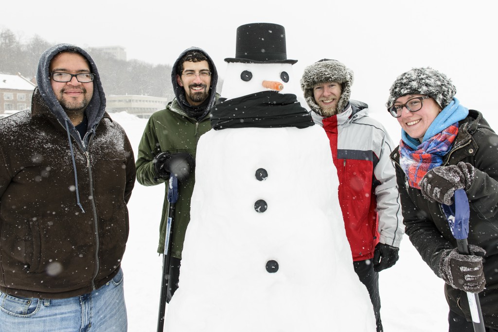 Bundled against the cold, a group of UW-Madison students are pictured with a carrot-nosed snowman they built on the lake.