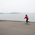 While many Badgers have left campus for winter break, a lone woman rolls her longboard alongside a partially frozen Lake Mendota on Sunday, Dec. 21. Picnic Point is pictured in the background. 