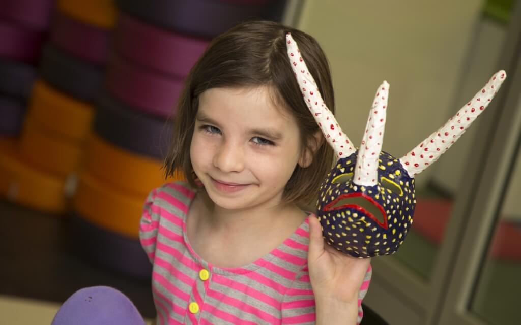 Nine-year-old Grace Halverson, daughter of UW–Madison education researchers Erica and Rich Halverson, shares a handmade mask created at The Bubbler. 