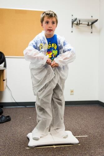 Xavier practices getting dressed in a translucent rain suit as sensors from the video-game system monitor his joint movements.