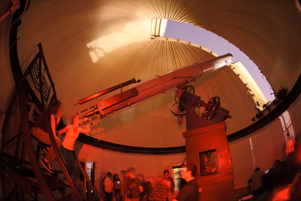 With moonlight shining in an open slit of the Washburn Observatory dome, the general public takes advantage of a once-monthly opportunity for nighttime public viewing of the stars using the observatory's vintage telescope in 2012. 