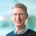 Portrait of Paul Ahlquist standing next to the atrium of the Discovery Building