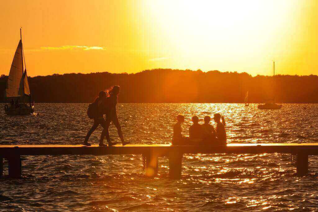 As the sun sets, UW–Madison students and visitors enjoy a cool summer evening on a Lake Mendota pier in July 2013.