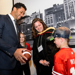 Commencement speaker Russell Wilson, Super Bowl winning quarterback for the Seattle Seahawks and former Badger football star, talks with Leah Olson, graduating with a master's in social work, and her son, Dylan.