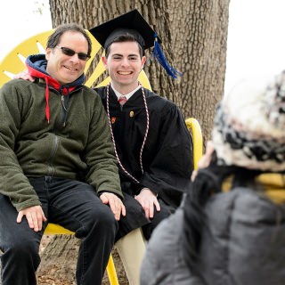 Graduate Zack Rosen is pictured with his father in a jumbo chair on the Memorial Union Terrace after commencement.