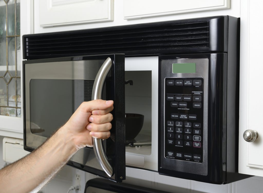 Photo: Hand opening microwave oven