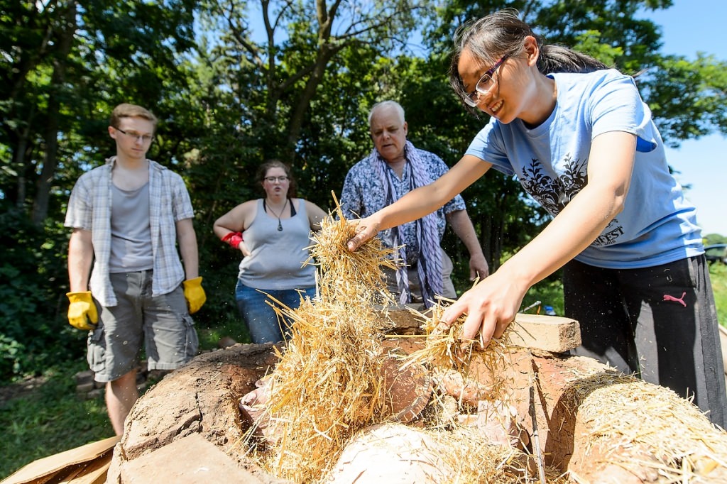 Photo: Student spreading straw over kiln