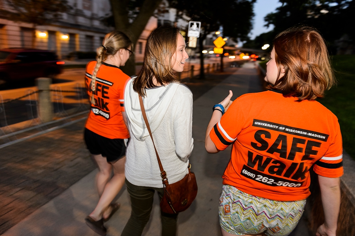 SAFEwalk staff members escort a UW–Madison student. SAFEwalk is a free campus service that provides trained, two-person walking escorts throughout the main campus.