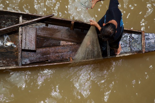 Photo: Man on boat pulling up fishing net