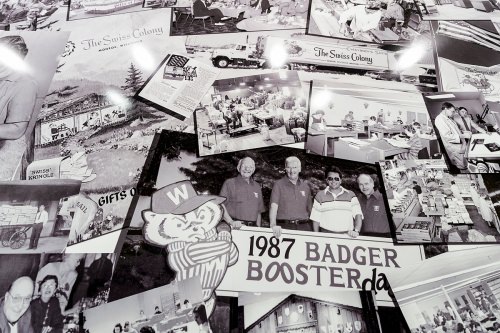 Pat Kubly, chairman of the board of Colony Brands and son of Ray Kubly, Sr., is pictured standing with his hand above the date 1987 in a collage of historical company photos on display at Colony Brands.