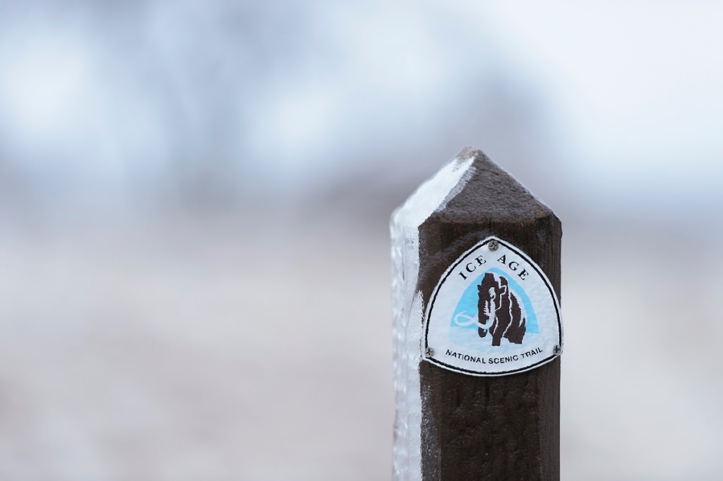 As day falls to dusk during winter on Feb. 22, 2017, a misty-freezing rain falls and a layer of ice coats a sign and prairie plants along a segment of the aptly named Ice Age National Scenic Trail that passes through the University Ridge golf course at the University of Wisconsin-Madison. (Photo by Jeff Miller/UW-Madison)