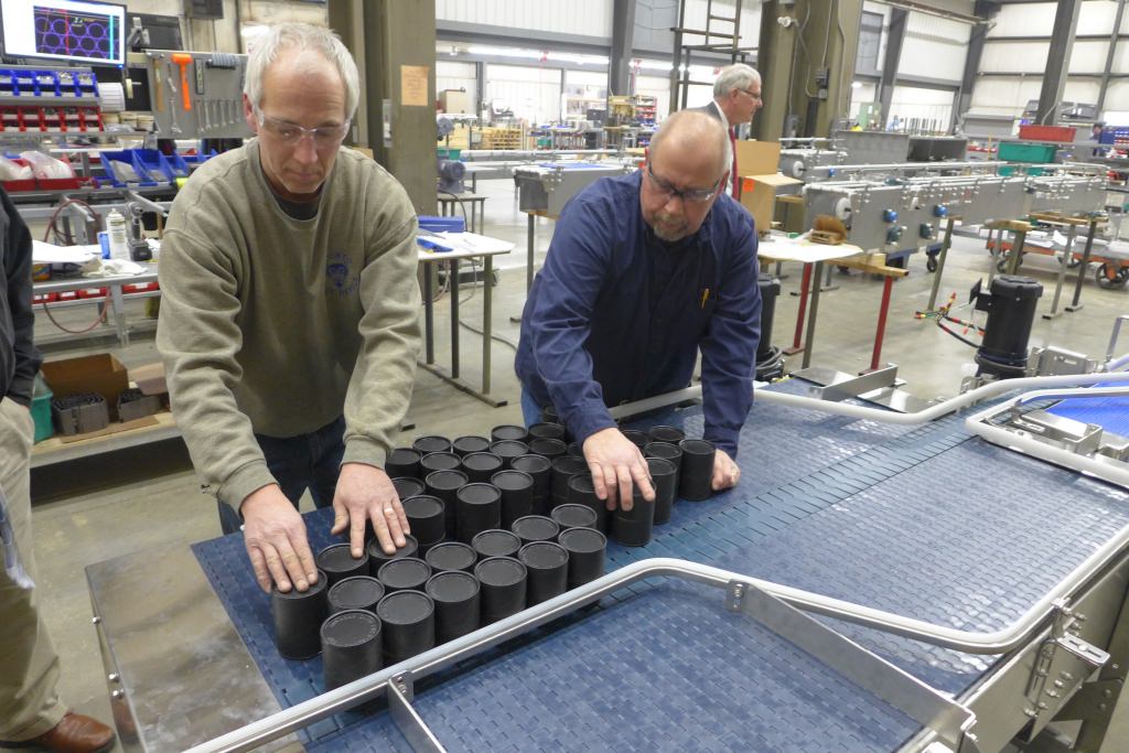 Photo: Men looking at containers on conveyor belt