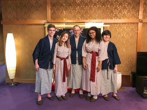 Adam L. Kern, center, and his students, attired in traditional Japanese robes for kicking back, in front of a formal kimono. Taken at the “Fujiya Kichō” traditional Japanese inn (ryōkan) in Chiba Prefecture. 