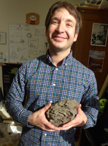 John Husson, a post-doctoral researcher working with Shanan Peters, holds a stromatolite, a biologically based structure that was much more common early in Earth history. 