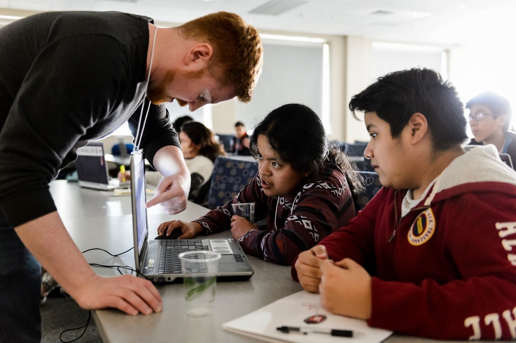 Photo: Instructor and students gathered around laptop screen