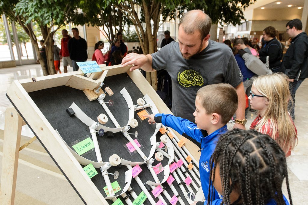 Josh Knackert (left), graduate student in biochemistry, works with young participants at a "Choose Your Own Fate" info booth at the Wisconsin Science Festival, a statewide celebration of curiosity and science exploration from Oct. 22-25, 2015. (Photo by Bryce Richter / UW–Madison)