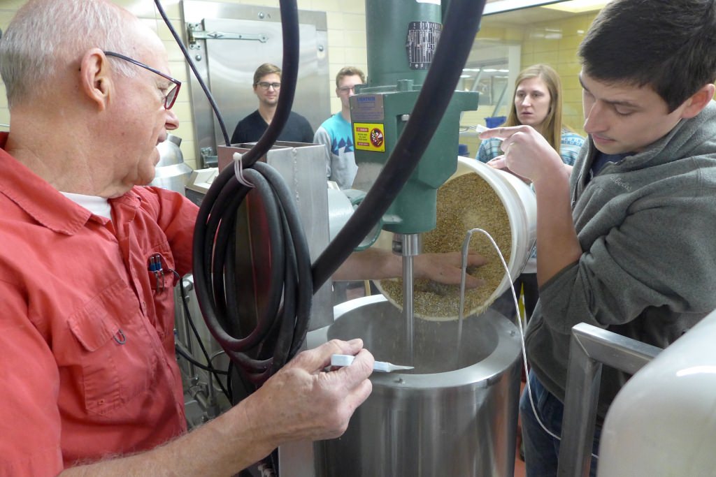 Instructor Hans Zoerb (left) and student Leo Gallagher pour malted barley into the mash tun at the UW–Madison Craft Brewery in Babcock Hall at UW–Madison, starting the brewing process for one of the six beers that were considered for production this spring. 