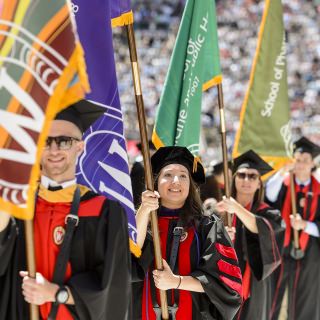 Flag bearers representing the 13 schools and colleges make their way down the center aisle.