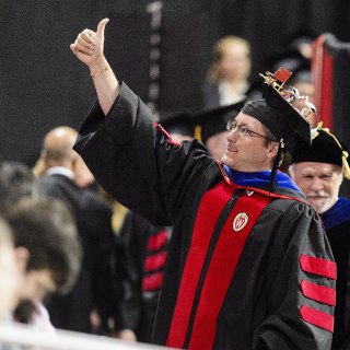 James Burnham gives a thumbs upon receiving his doctorate in forest and wildlife ecology. On his mortarboard is a model of the habitat of the Siberian crane.