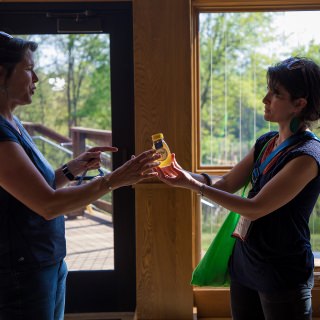 Wisconsin Idea Seminar Director Catherine Reiland (right) presents honey collected around Madison to Marcy West (left), executive director of the Kickapoo Valley Reserve. Local gifts produced in Madison were a way for seminar participants to show appreciation for presenters who shared their own experiences.