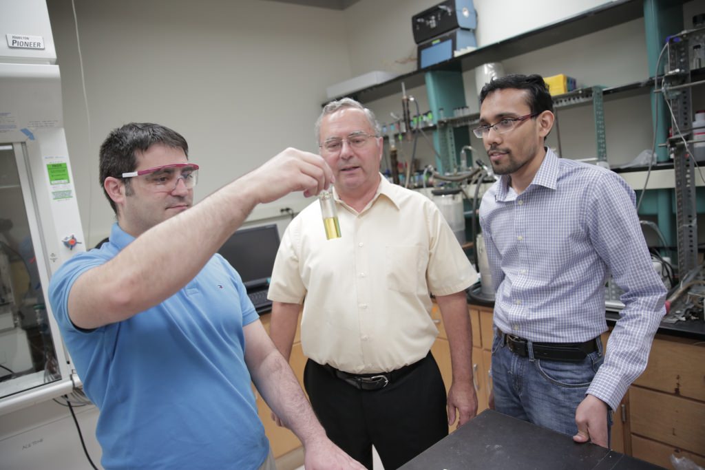 UW–Madison engineers, from left, David Martin Alonso, James Dumesic and Ali Hussain Motagamwala, examine a vial of furfural, one of a group of valuable products the researchers can now create as part of the biofuel refining process. 