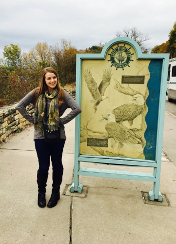 Photo: Olivia Sanderfoot posing in front of sign with pictures of Eagles