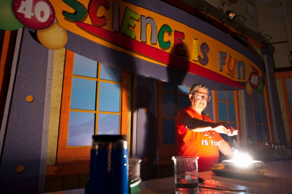 Photo: Bassam Shakhashiri presenting science show in dark room illuminated from lab bench