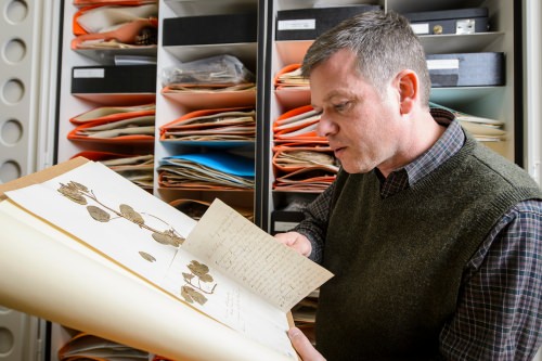 Photo: Ken Cameron looking at book of plant samples