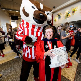 Photo: Bucky Badger with Rebecca Blank, holding stack of books