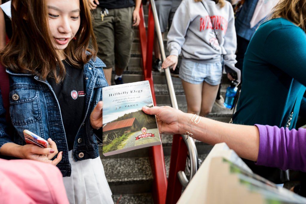 Photo: Volunteer handing book to student