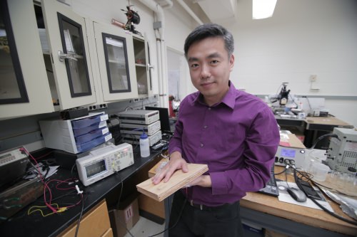 Photo: Xudong Wang holding piece of wood used in energy-harvesting flooring