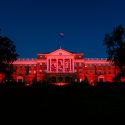 n honor of UW-Madison's Homecoming Week, red-colored accent lighting illuminates the exterior of Bascom Hall and terrace plantings surrounding the Abraham Lincoln statue at the University of Wisconsin-Madison as dawn brightens the night sky on Oct. 20, 2017. Hanging between the building's column is a graphic banner of UW-Madison mascot Bucky Badger. (Photo by Jeff Miller / UW-Madison)