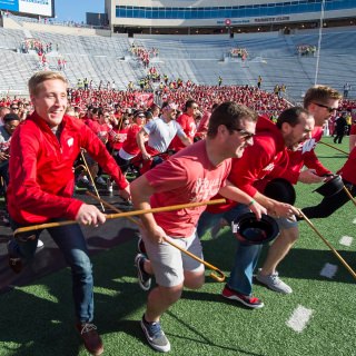 Law School students prepare to run the length of the field and take part and in the annual Cane Toss event just before the start of the UW Homecoming football games versus Maryland inside Camp Randall Stadium at the University of Wisconsin-Madison on Oct. 21, 2017. While the origin of this 1930s-era tradition is murky, the goal for the third-year law students is to toss their canes over the goal post and catch them on the other side. Legend holds that those who do so successfully will win their first legal cases; those who don't, or catch the wrong cane, will have to settle. (Photo by Bryce Richter / UW-Madison)