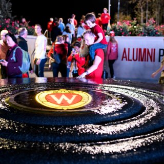 A water fountain with illuminated W Crest flows as guests explore the recently-opened Alumni Park at the University of Wisconsin-Madison during the UW Homecoming Block Party on Oct. 20, 2017. The event followed the Homecoming Parade that took place earlier in the evening. (Photo by Jeff Miller / UW-Madison)