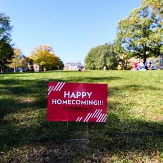 An advertising sign promoting a Happy Homecoming is posted at the base of Bascom Hill at the University of Wisconsin-Madison during autumn on Oct. 18, 2017. (Photo by Jeff Miller / UW-Madison)