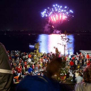 UW alumni and members of the Madison community take in a fireworks display over Lake Mendota at the Memorial Union Terrace during the UW Homecoming Block Party at Alumni Park at the University of Wisconsin-Madison on Oct. 20, 2017. The event followed the Homecoming Parade that took place earlier in the evening. (Photo by Bryce Richter / UW-Madison)