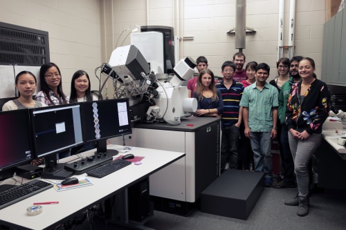 Photo: Students standing around microscope