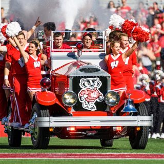 Members of UW Spirit Squad ride the Bucky Wagon onto the field at Camp Randall Stadium before the homecoming football game. The driver of Bucky Wagon is Glenn Bower, the manager of the wagon and automotive faculty adviser for UW-Madison's College of Engineering (Photo by Jeff Miller/UW-Madison)