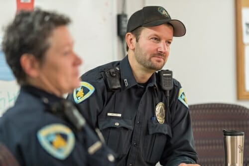 Photo: Police officers sitting at table listening to briefing