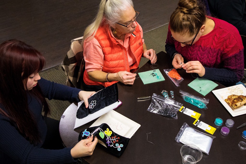 Wunk Sheek student leader Grace Armstrong, right, demonstrates her beading skills on a pair of Native American earrings. To celebrate Native American Heritage Month, student group Wunk Sheek hosted a bead workshop designed to teach contemporary Native American styles at Chadbourne Residence Hall at the University of WisconsinÐMadison in Madison, WI on Tuesday, November 14, 2017. (Photo by Nate Moll | University Communications)