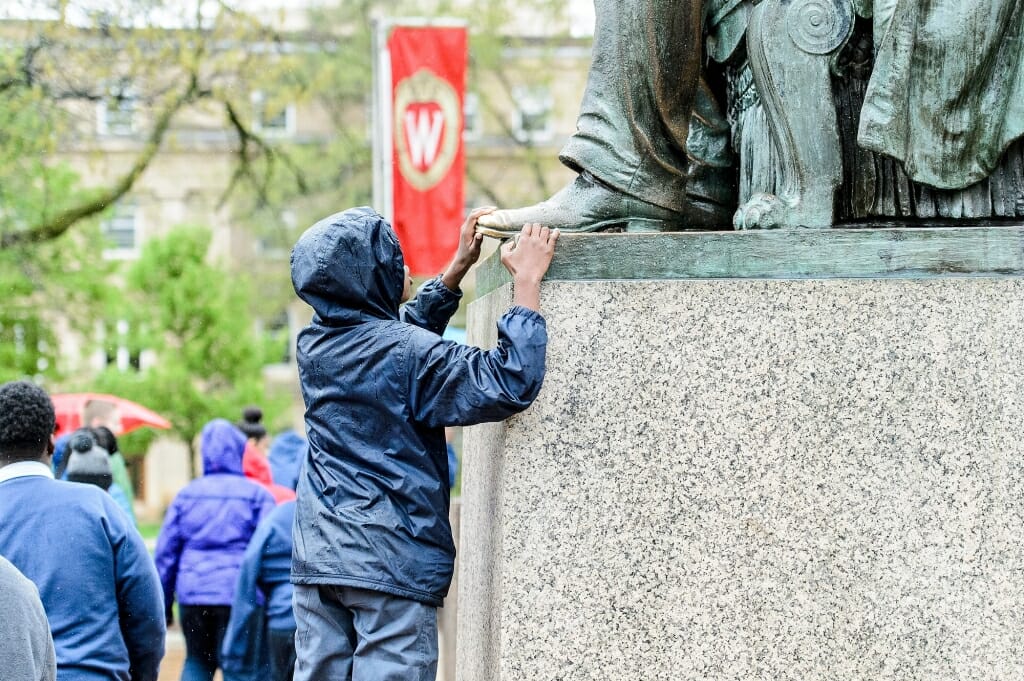 Photo: Young student touching foot of Lincoln statue