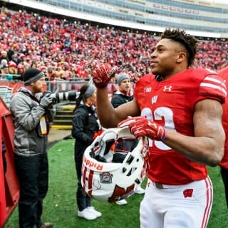 Wisconsin running back Jonathan Taylor (23) waves to cheering Wisconsin Badger fans following Wisconsin's 24-10 football victory over the Michigan Wolverines at Camp Randall Stadium at the University of Wisconsin-Madison on Nov. 18, 2017. (Photo by Jeff Miller / UW-Madison)