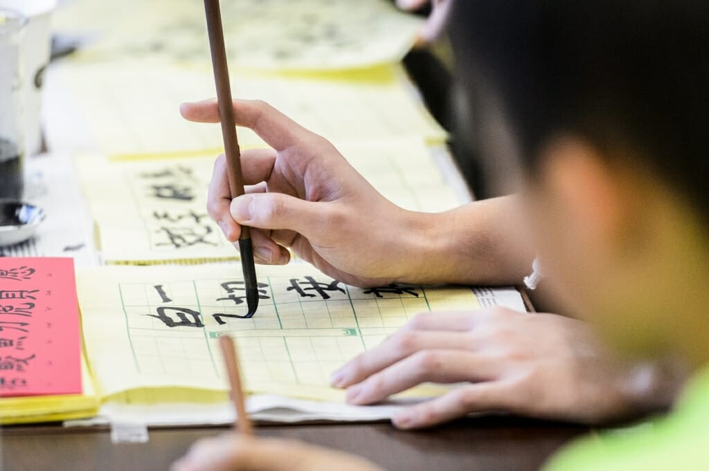 Attendees practice writing in Chinese with pen and ink at a Chinese American Student Association (CHASA) booth during a Japanese Student Association (JSA) cultural celebration event inside Ingraham Hall at the University of Wisconsin-Madison on Dec. 2, 2017. The event was a collaborative effort with a number of UW student organizations to promote Asian culture. (Photo by Bryce Richter / UW-Madison)