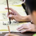 Attendees practice writing in Chinese with pen and ink at a Chinese American Student Association (CHASA) booth during a Japanese Student Association (JSA) cultural celebration event inside Ingraham Hall at the University of Wisconsin-Madison on Dec. 2, 2017. The event was a collaborative effort with a number of UW student organizations to promote Asian culture. (Photo by Bryce Richter / UW-Madison)