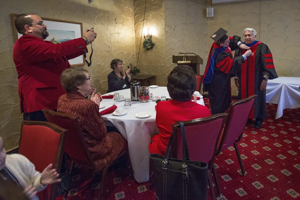 Photo of Jeremy Foltz, chair of the department of agricultural economics, putting on a doctoral hood to Luciano Barraza, right, at the University Club Sunday before the ceremony.