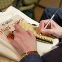 Photo: Closeup of a person's hand writing in a notebook